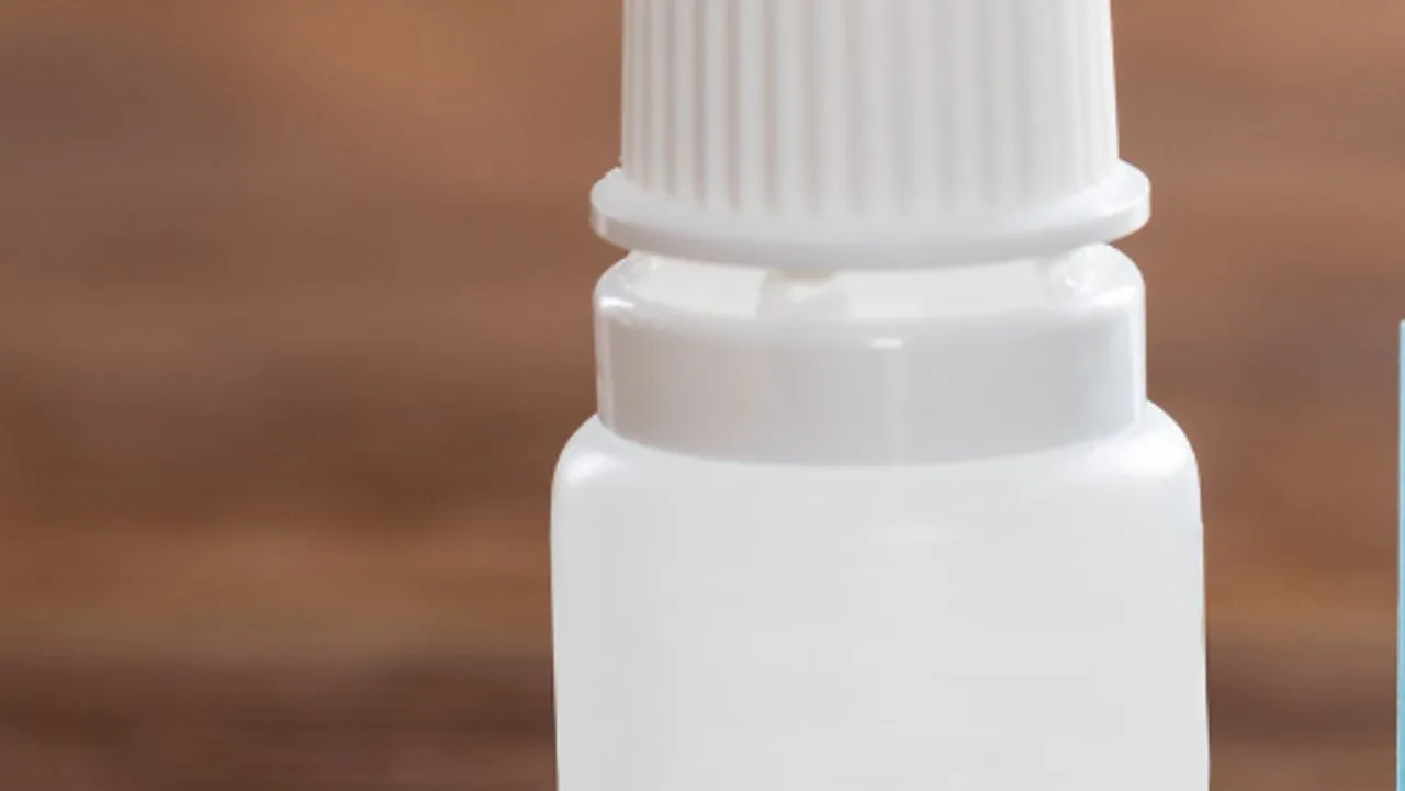 Personne instillant une goutte de larmes artificielles dans l'œil